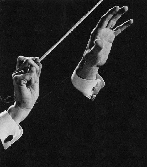A conductor’s hands directing with a baton